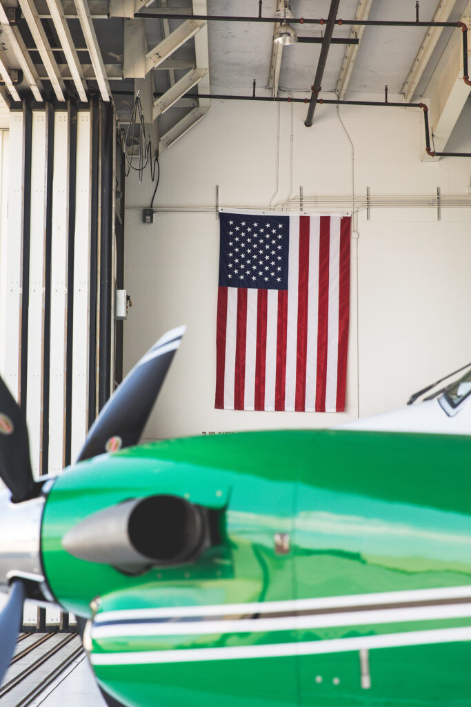 N716WL-54-green-charter-plane-parked-in-front-of-american-flag-on-wall