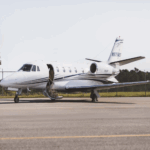 Private jet N975MD parked on airport tarmac with trees in background